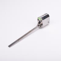 Oval låscylinder i silverfärgad metall med en lång, platt, räfflad metall medbringare.