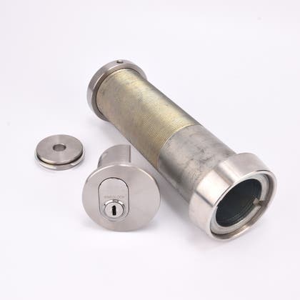 Cylindrisk silverfärgat nyckelfacksrör samt ett runt lås och en rund bricka.