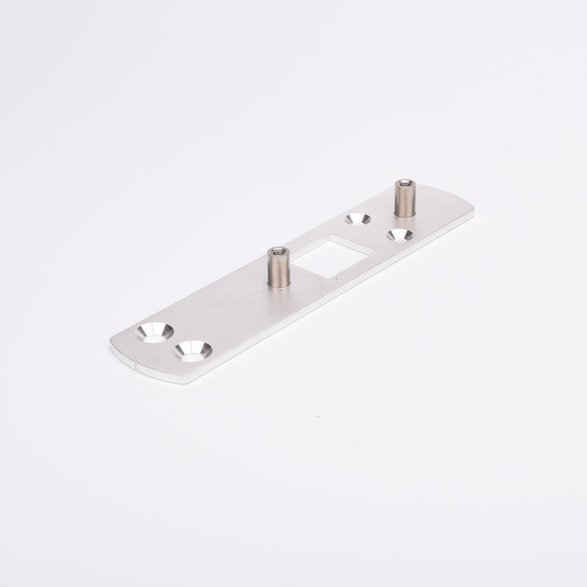 Rektangulär metallplatta med två cylindriska distanser och fyra försänkta hål, symmetriskt placerade. Plattan har även ett rektangulärt urtag i mitten.