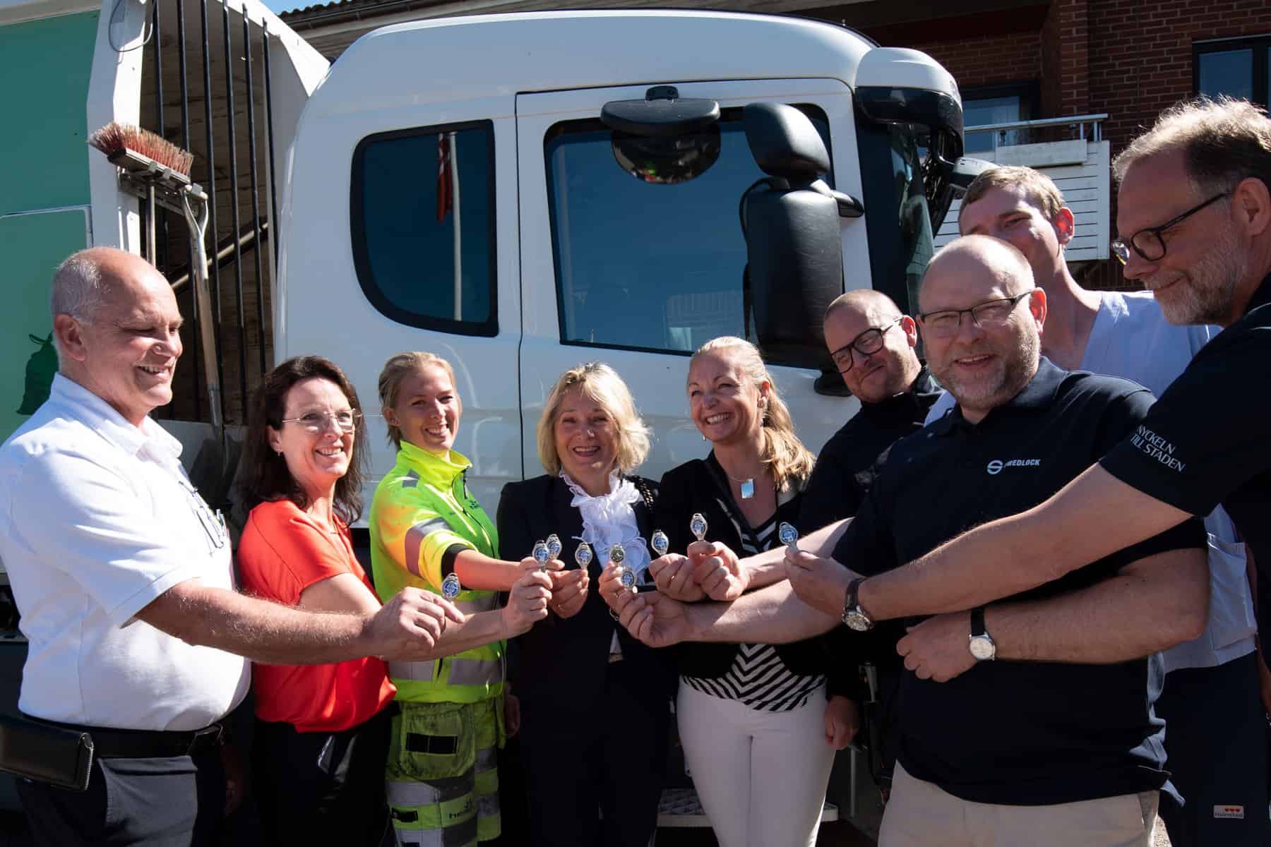 En grupp glada människor hållandes Swedlock nycklar framför en vit lastbil