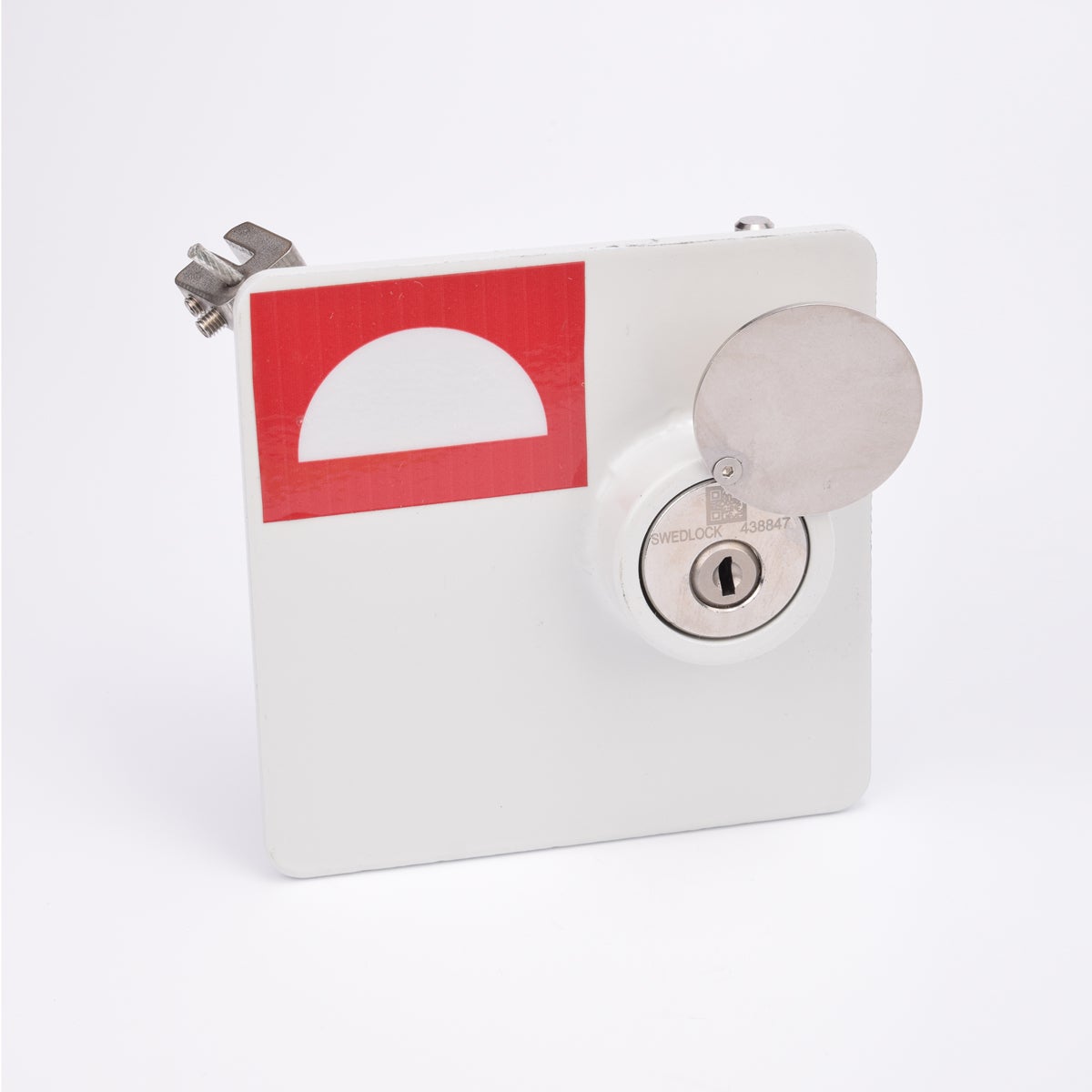 Vit fyrkantig brandlucka i metall med nyckelhål och vridbar skyddskåpa.