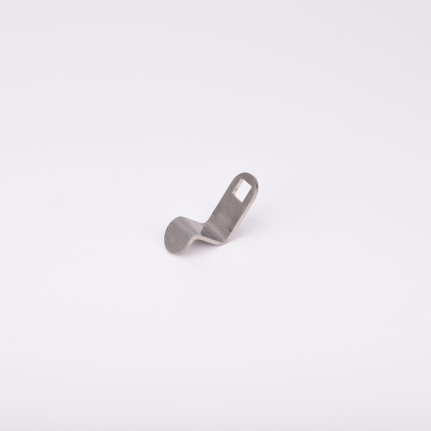 Liten rigel i metall med en platt, cirkulär bas som böjer sig uppåt till en vinklad rektangulär sektion med ett rektangulärt urtag nära toppen.