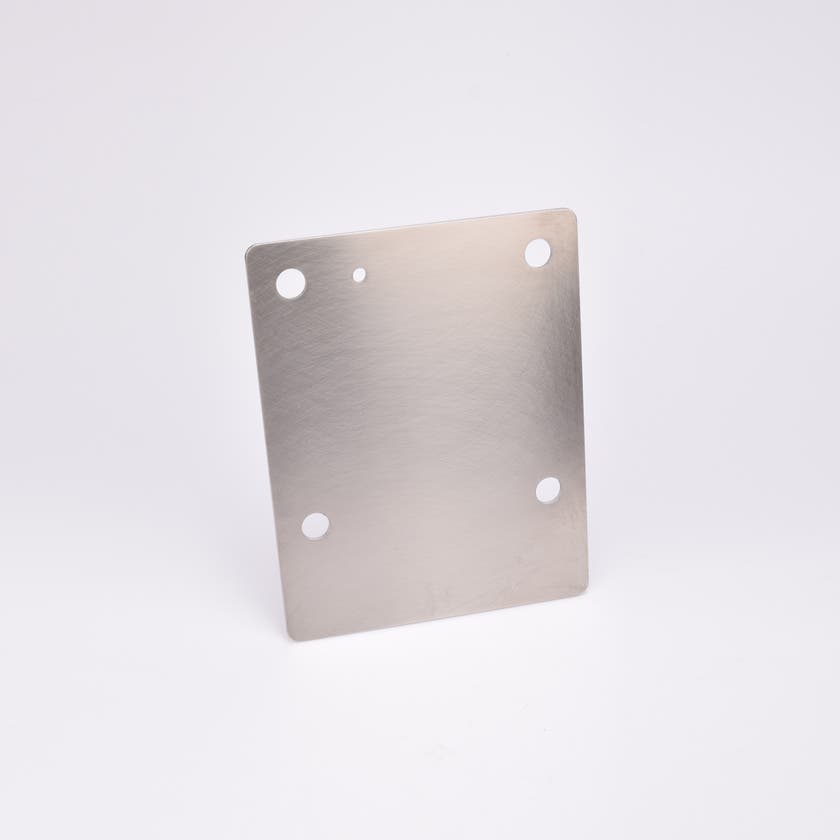 Rektangulär metallplatta med fyra runda hål.