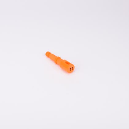 Orange användarpegg med cylindrisk form och flera sektioner med olika diameter. Ena änden är ihålig med ett avlångt spår, medan den motsatta änden har en räfflad yta.