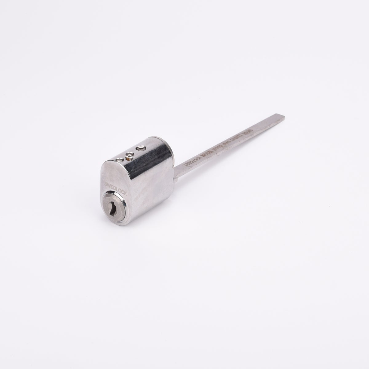 Oval låscylinder i silverfärgad metall med en lång, platt, räfflad metall medbringare.