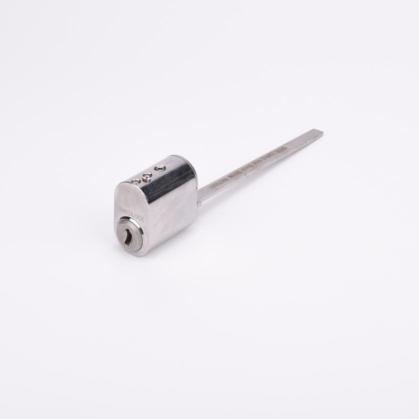 Oval låscylinder i silverfärgad metall med en lång, platt, räfflad metall medbringare.