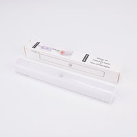 Vit LED-lampa med rörelsesensor, liggande framför sin förpackning.