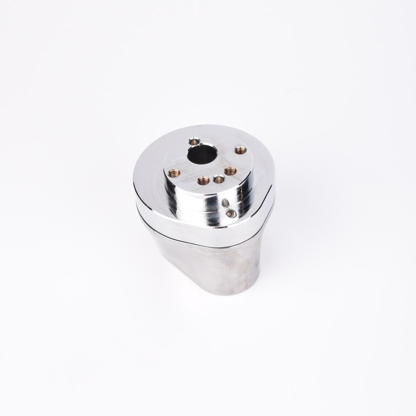 Silverfärgad metallkropp med rundad bas och flera hål på ovansidan.