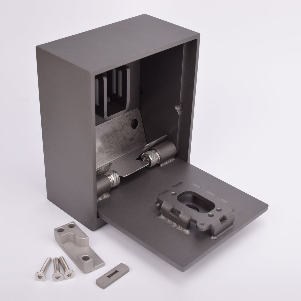 Grått fasadnyckelskåp i metall, luckan är i öppet läge och framför skåpet ligger tre skruvar och två metallbitar.