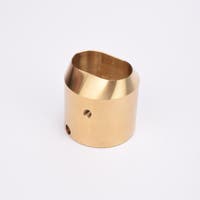 Mässingsfärgat utfyllnadsadapter i metall med snedskuren topp som bildare en oval öppning.