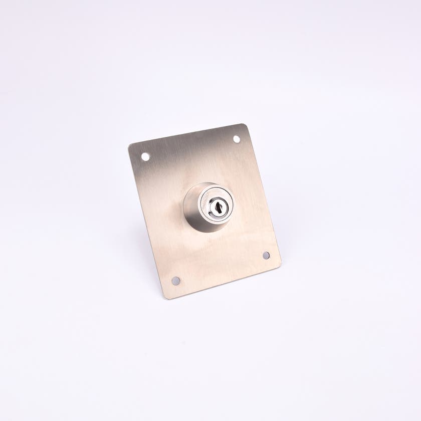 En rektangulär metallplatta med ett cylinderlås i mitten och fyra hål i hörnen.
