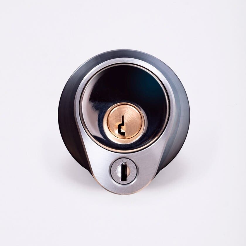 Närbild av ett silverfärgat säkerhetslås med två nyckelhål, placerade ovanför varandra.