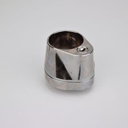 Droppformat metallhus med runt urtag för låscylinder, samt nyckelhål i nedre avsmalnande delen.