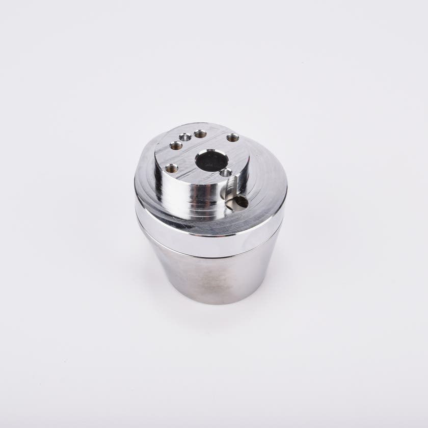 Silverfärgad metallkropp med rundad bas och flera hål på ovansidan.