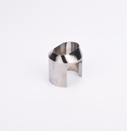 Polerad metallkomponent med cylindrisk form, vinklad topp och två ovala utskärningar.