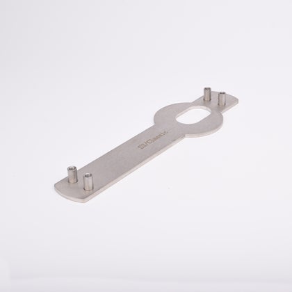 Monteringsplåt avlång, platt kropp och ovalt urtag i mitten samt fyra vertikala cylindriska tappar, två i vardera ände.