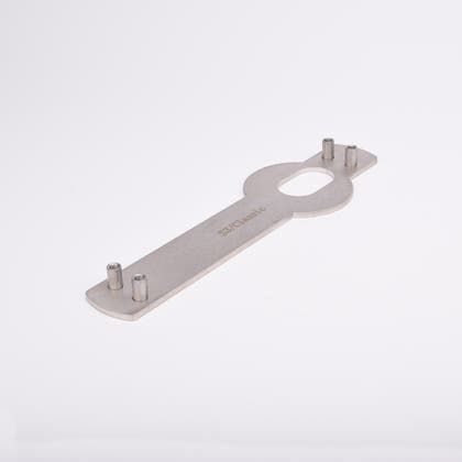 Monteringsplåt avlång, platt kropp och ovalt urtag i mitten samt fyra vertikala cylindriska tappar, två i vardera ände.