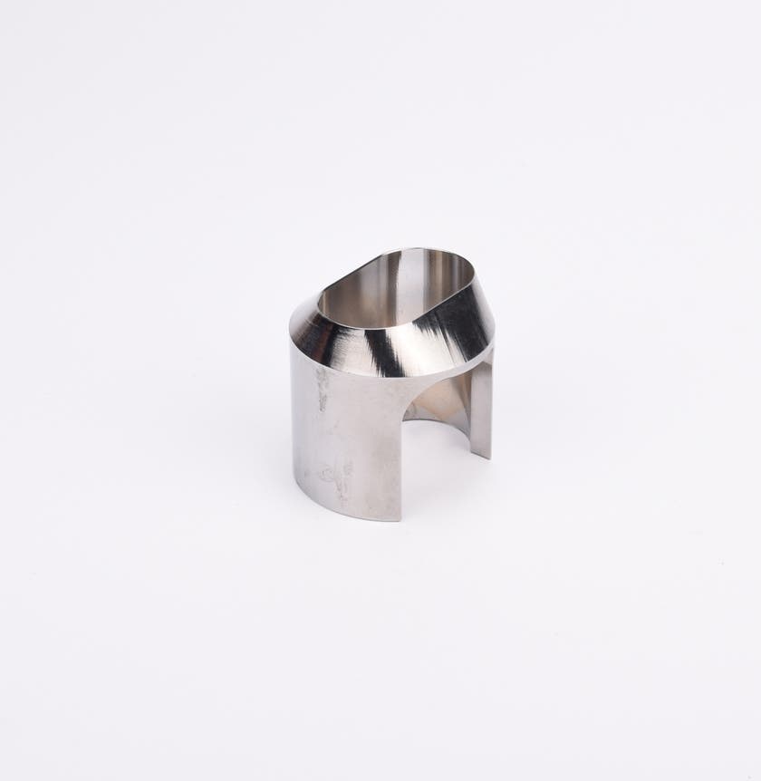 Polerad metallkomponent med cylindrisk form, vinklad topp och två ovala utskärningar.