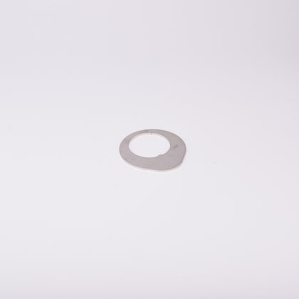 Distansbricka i metall med oregelbunden form och ett centralt hål.