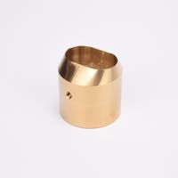 Mässingsfärgat utfyllnadsadapter i metall med snedskuren topp som bildar en oval öppning.