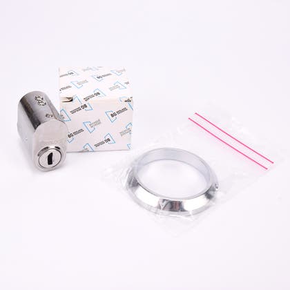 Ovalt cylinderlås i metall med tillhörande metallring och kartong.