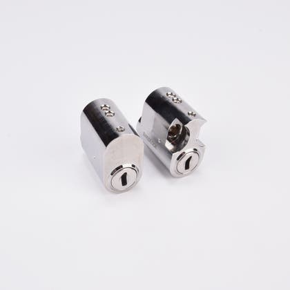 Två ovala cylinderlås i metall med nyckelhål.