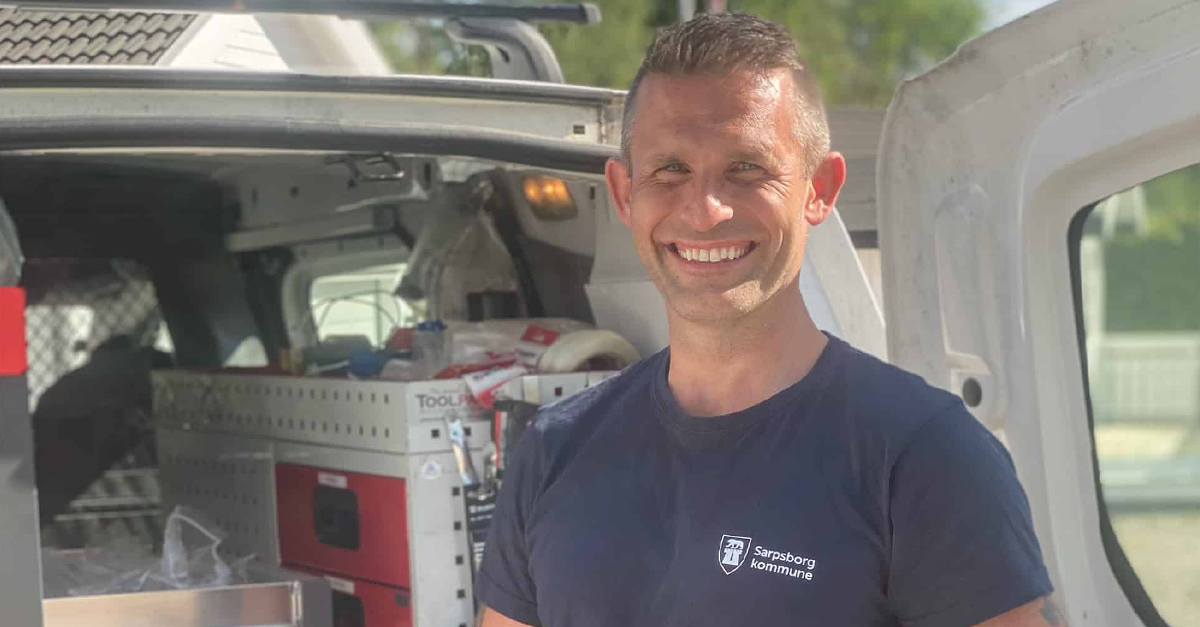 En leende man framför en öppen bagagelucka