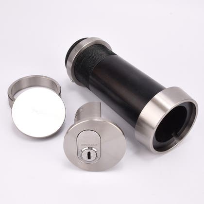 Cylindrisk nyckelfacksrör med svart kropp och silverfärgade ändar, samt ett runt lås och en rund bricka.