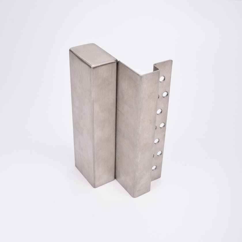 En L-formad nyckelförvaringsenhet med flera cirkulära hål längs ena sidan.