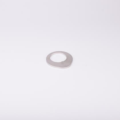 Distansbricka i metall med oregelbunden form och ett centralt hål.