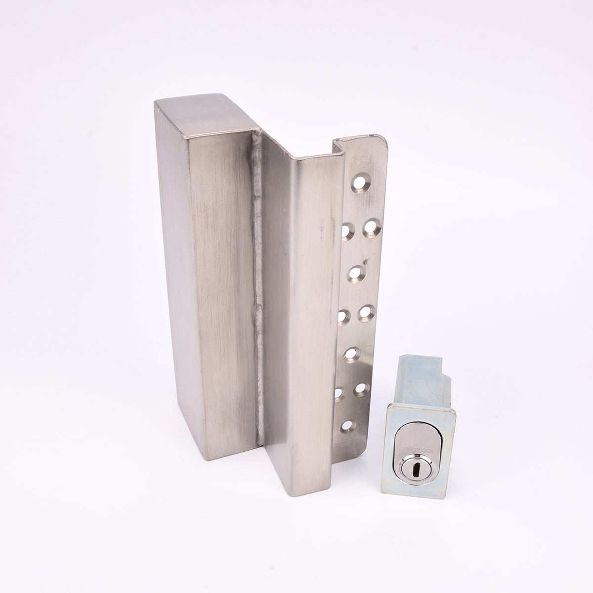 Två metallföremål visas. Det större är en L-formad nyckelförvaringsenhet med flera cirkulära hål längs ena sidan. Det mindre är en rektangulär cylinderhållare med en oval cylinder.