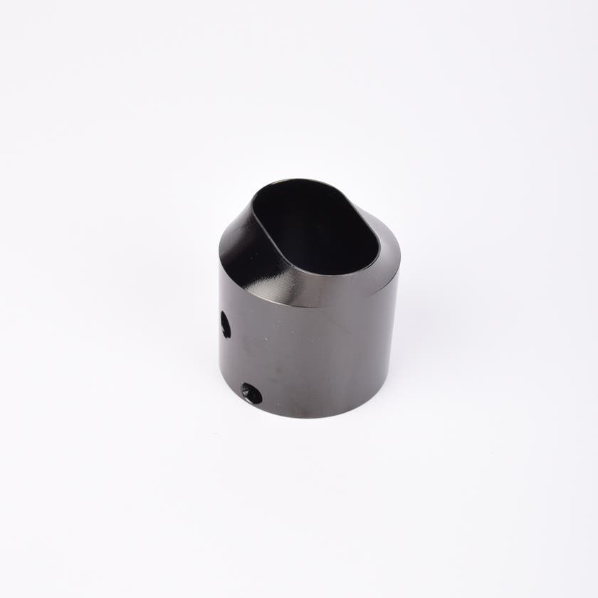 Svart utfyllnadsadapter i metall med snedskuren topp som bildar en oval öppning.