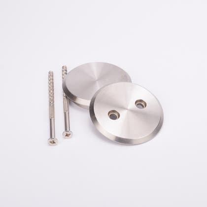 Två rostfria skruvar och två runda täcklocksbrickor i metall med två runda hål.