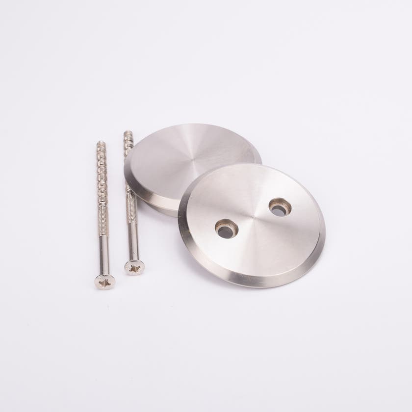 Två rostfria skruvar och två runda täcklocksbrickor i metall med två runda hål.
