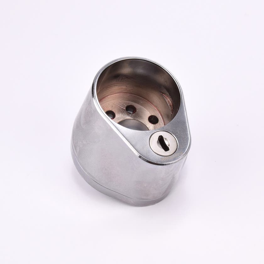 Droppformad Duo City i metall med rundad topp och cirkulär öppning i mitten, lätt avsmalnande mot basen där ett nyckelhål sitter.