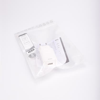 Vit USB-väggladdare, 230V till USB, förpackad i transparent plastpåse med etikett och bruksanvisning.