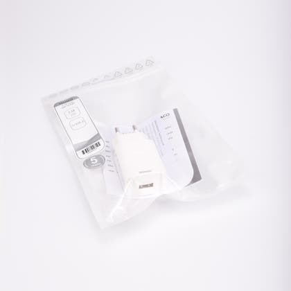Vit USB-väggladdare, 230V till USB, förpackad i transparent plastpåse med etikett och bruksanvisning.