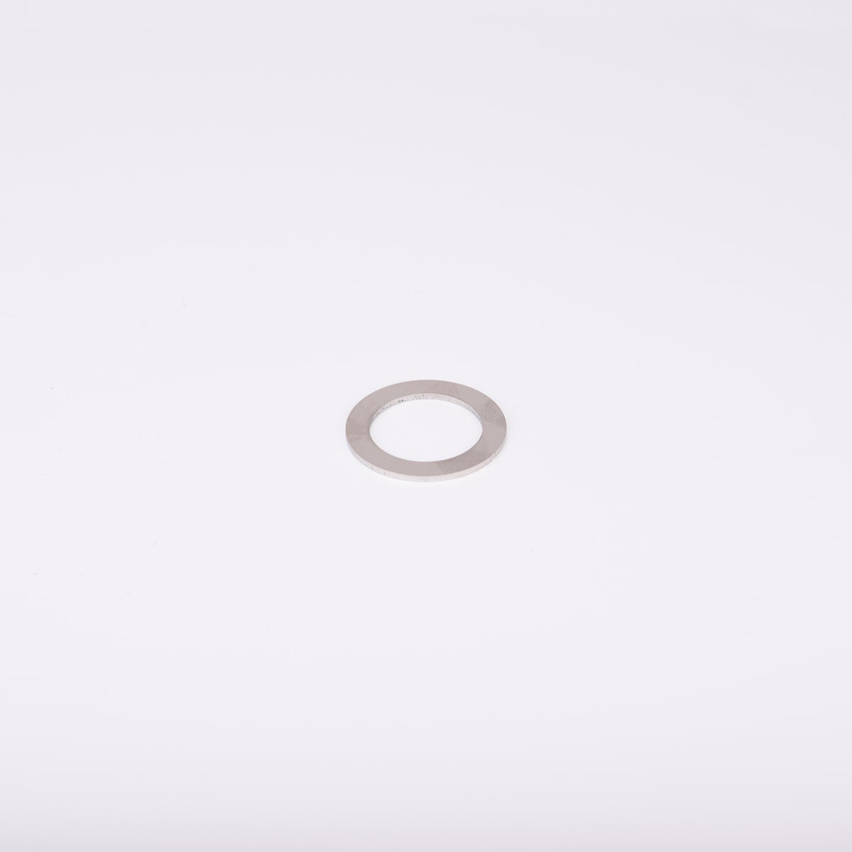 En distansbricka i metall med cirkulär form och ett centralt hål.