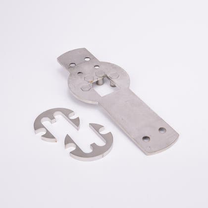 Tre metallkomponenter: en rektangulär platta med hål och utskärningar samt två halvcirkelformade delar med krokformade utskärningar.
