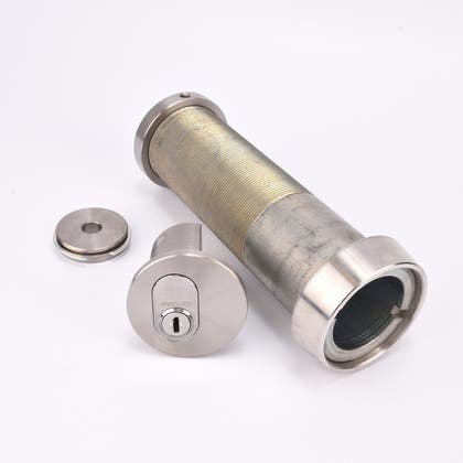 Cylindrisk silverfärgat nyckelfacksrör samt ett runt lås och en rund bricka.