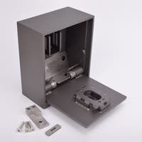 Grå metallisk fasadnyckelskåp med öppen lucka, framför ligger några skruvar och metallkomponenter.