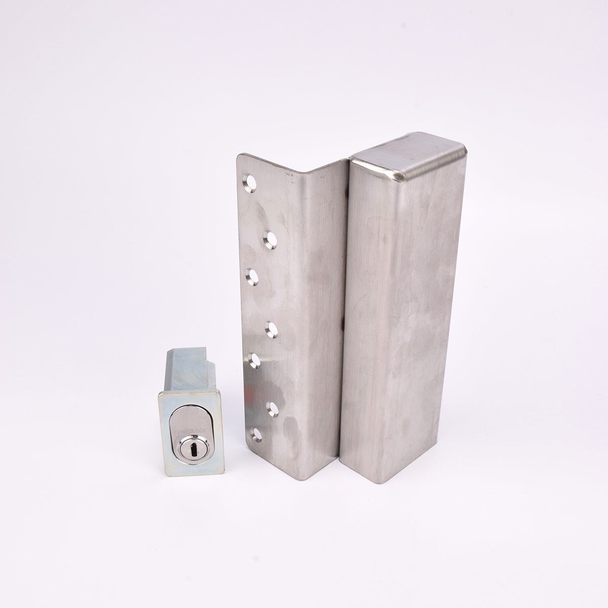 Två metallföremål visas. Det större är en L-formad nyckelförvaringsenhet med flera cirkulära hål längs ena sidan. Det mindre är en rektangulär cylinderhållare med en oval cylinder.