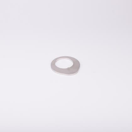 Distansbricka i metall med oregelbunden form och ett centralt hål.