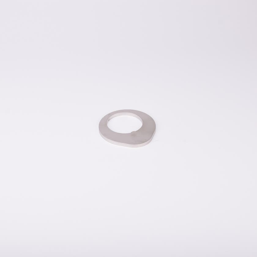 Distansbricka i metall med oregelbunden form och ett centralt hål.