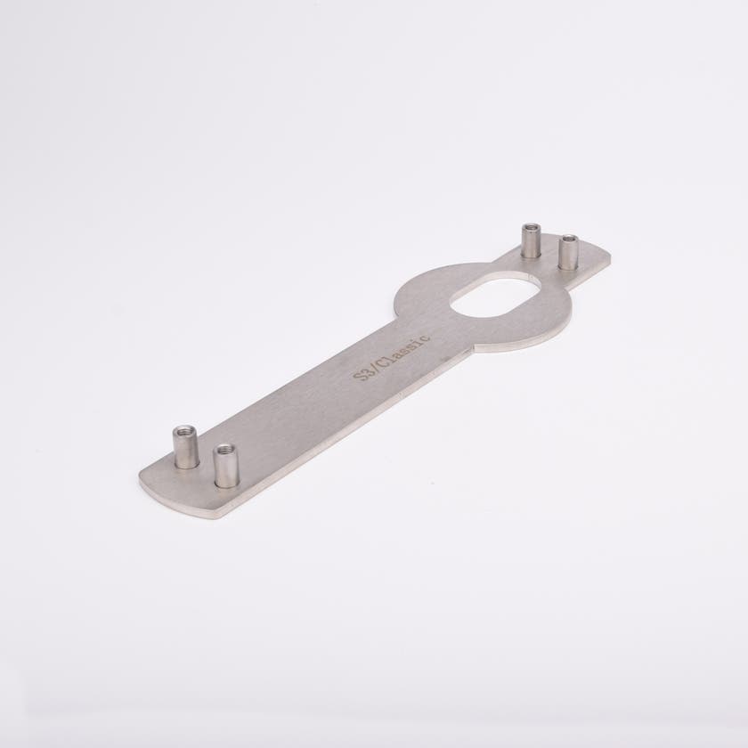 Monteringsplåt avlång, platt kropp och ovalt urtag i mitten samt fyra vertikala cylindriska tappar, två i vardera ände.