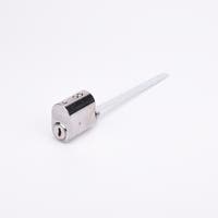 Oval låscylinder i silverfärgad metall med en lång, platt, räfflad medbringare i metall.