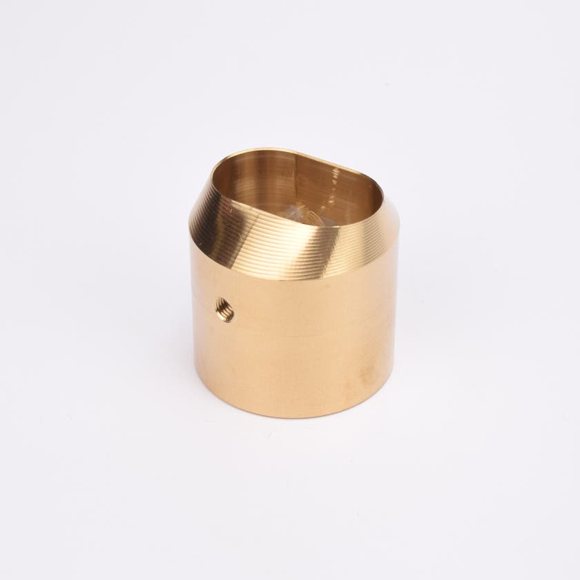 Mässingsfärgat utfyllnadsadapter i metall med snedskuren topp som bildar en oval öppning.