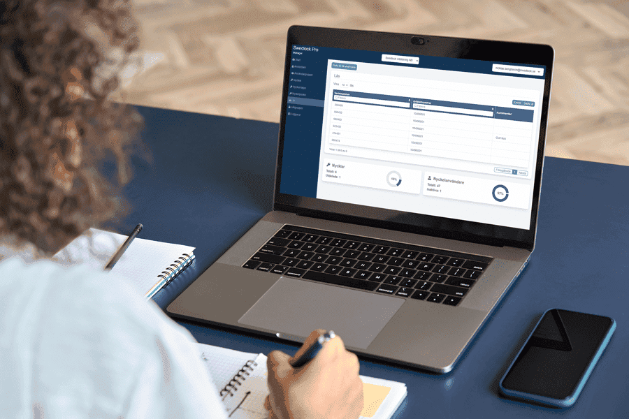 En hand som håller en mobiltelefon där en Swedlock nyckel får behörighet