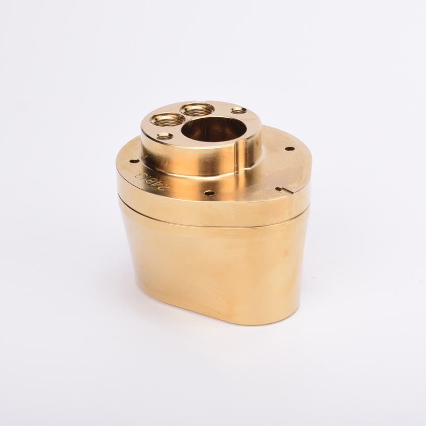 Mässingsfärgad metallkropp med rundad bas och flera hål på ovansidan.