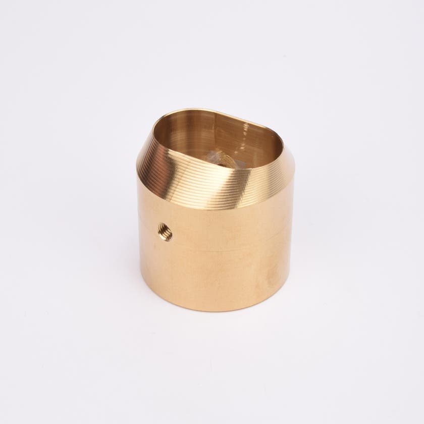 Mässingsfärgat utfyllnadsadapter i metall med snedskuren topp som bildare en oval öppning.